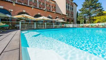 Una piscina al aire libre, sillones reclinables de piscina