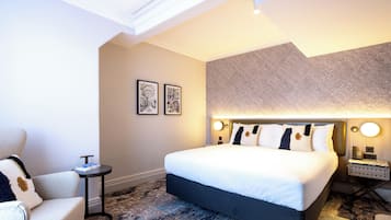 Una habitación de hotel moderna con una cama grande, una mesita auxiliar pequeña y una silla.