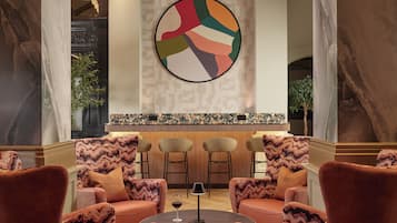 A lobby with a marble column, a modern bar area, and seating with patterned cushions.