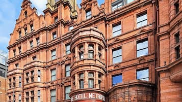 Un hotel histórico con una entrada destacada en esquina, amplias ventanas y detallado trabajo de ladrillo.