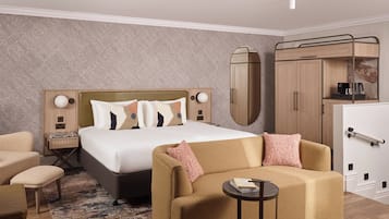 A hotel room with a bed, a sofa, a small table, a wardrobe, and a mirror.