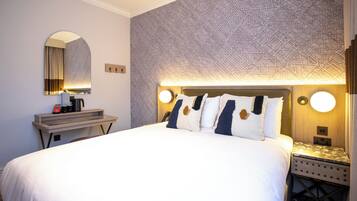 Ein Hotelzimmer mit einem großen Bett, einem Nachttisch, einem Spiegel und einer Wand mit geometrischem Muster.