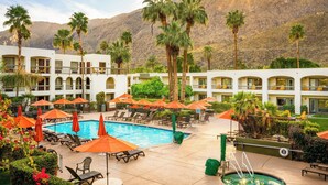 A hotel pool area with sun loungers, umbrellas, and palm trees. - Palm Mountain Resort and Spa (Palm Springs)