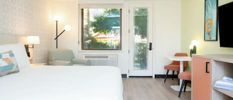 Habitación de hotel con cama, escritorio, silla, televisor y ventana con vistas al exterior.