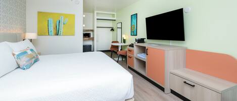 Una habitación de hotel con una cama, un escritorio, un televisor y obras de arte en las paredes.