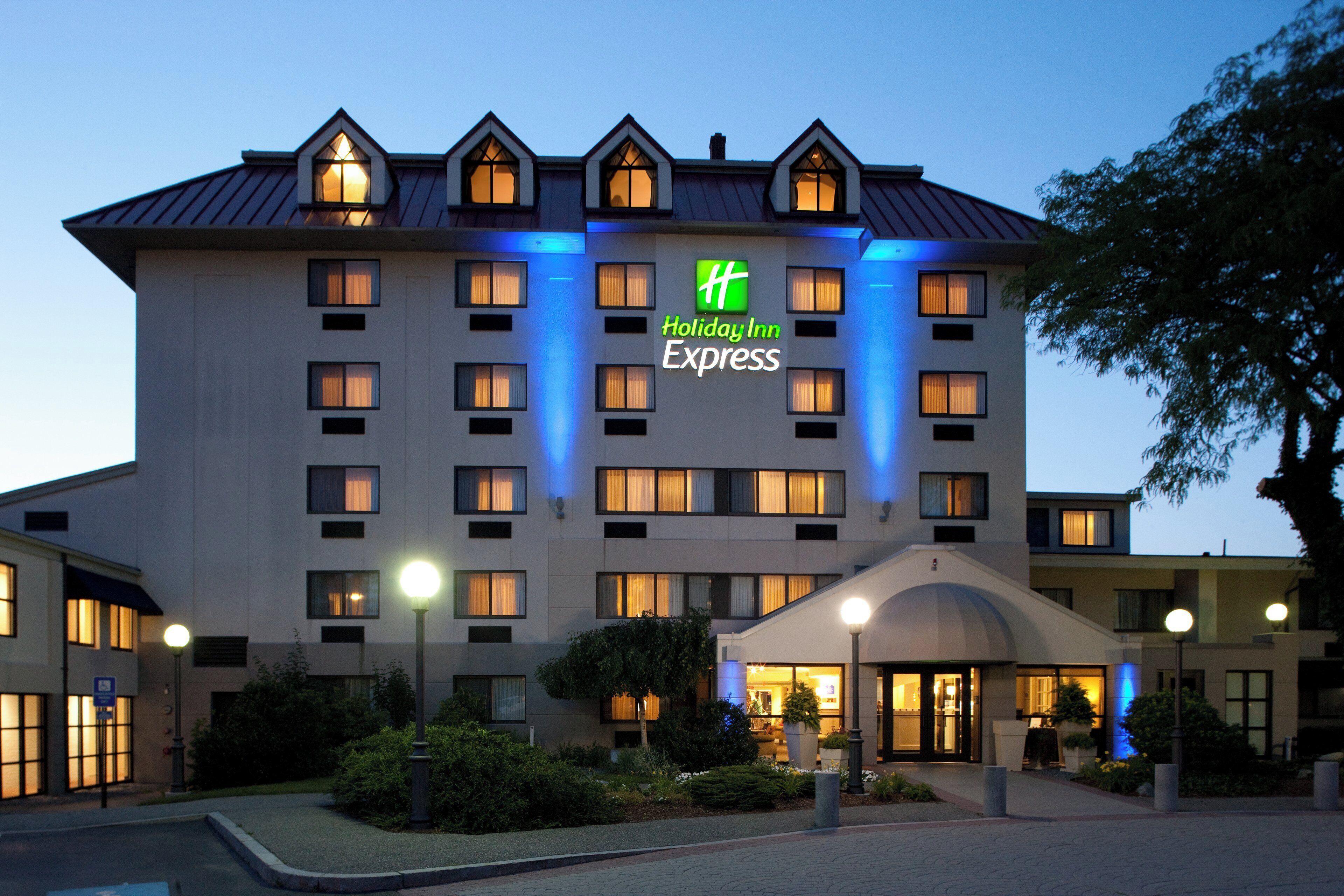 Um hotel Holiday Inn Express com fachada moderna, várias janelas e entrada bem iluminada.