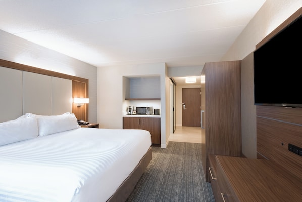 Una habitación de hotel con una cama grande, un escritorio con microondas y televisión.