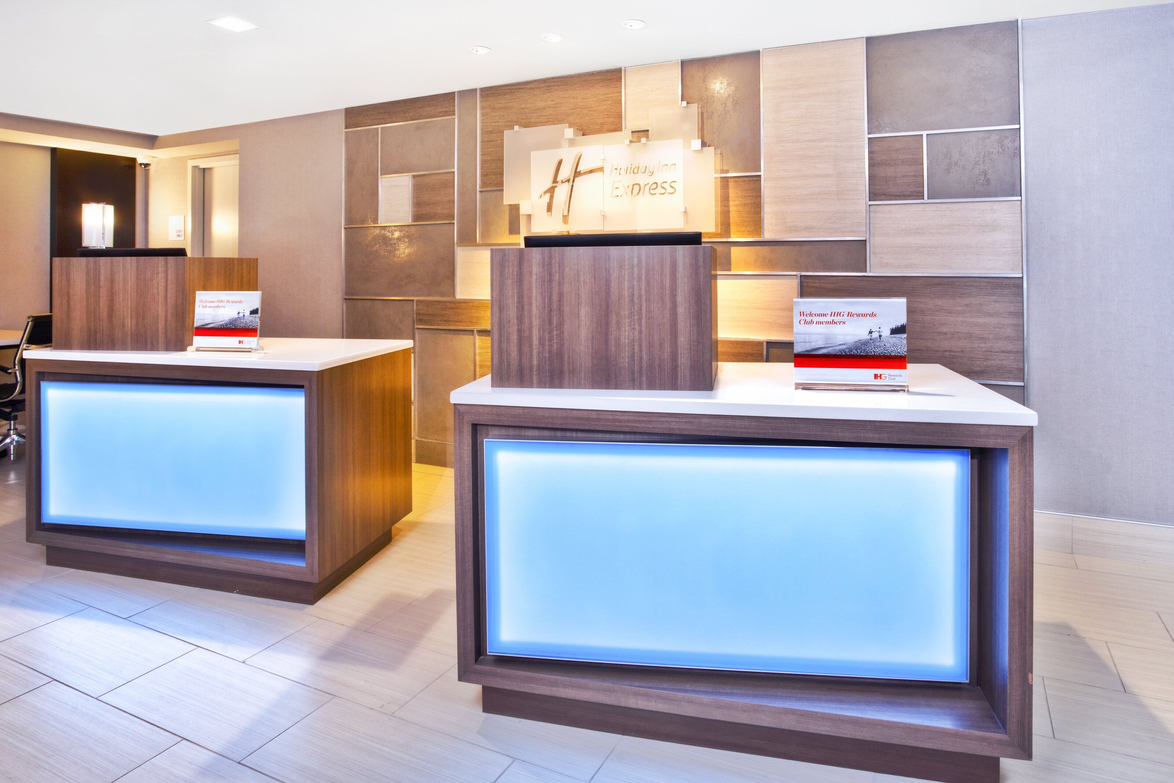 A reception area with two reception desks, each with a sign for Holiday Inn Express.