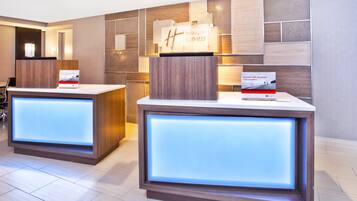 A reception area with two reception desks, each with a sign for Holiday Inn Express.