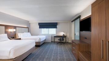 A hotel room with two beds, a desk, a chair, a TV, and a wardrobe.