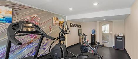 Un gimnasio con cintas de correr, elípticas y un dispensador de agua.
