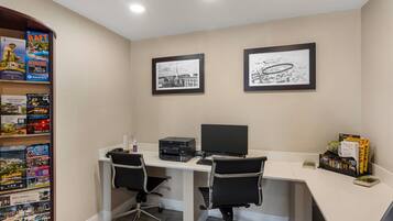 A modern office space with a desk, two chairs, a printer, and a bookshelf filled with travel guides.