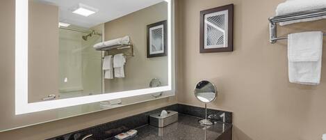 A modern bathroom with a large mirror, a sink, a toilet, and a shower.