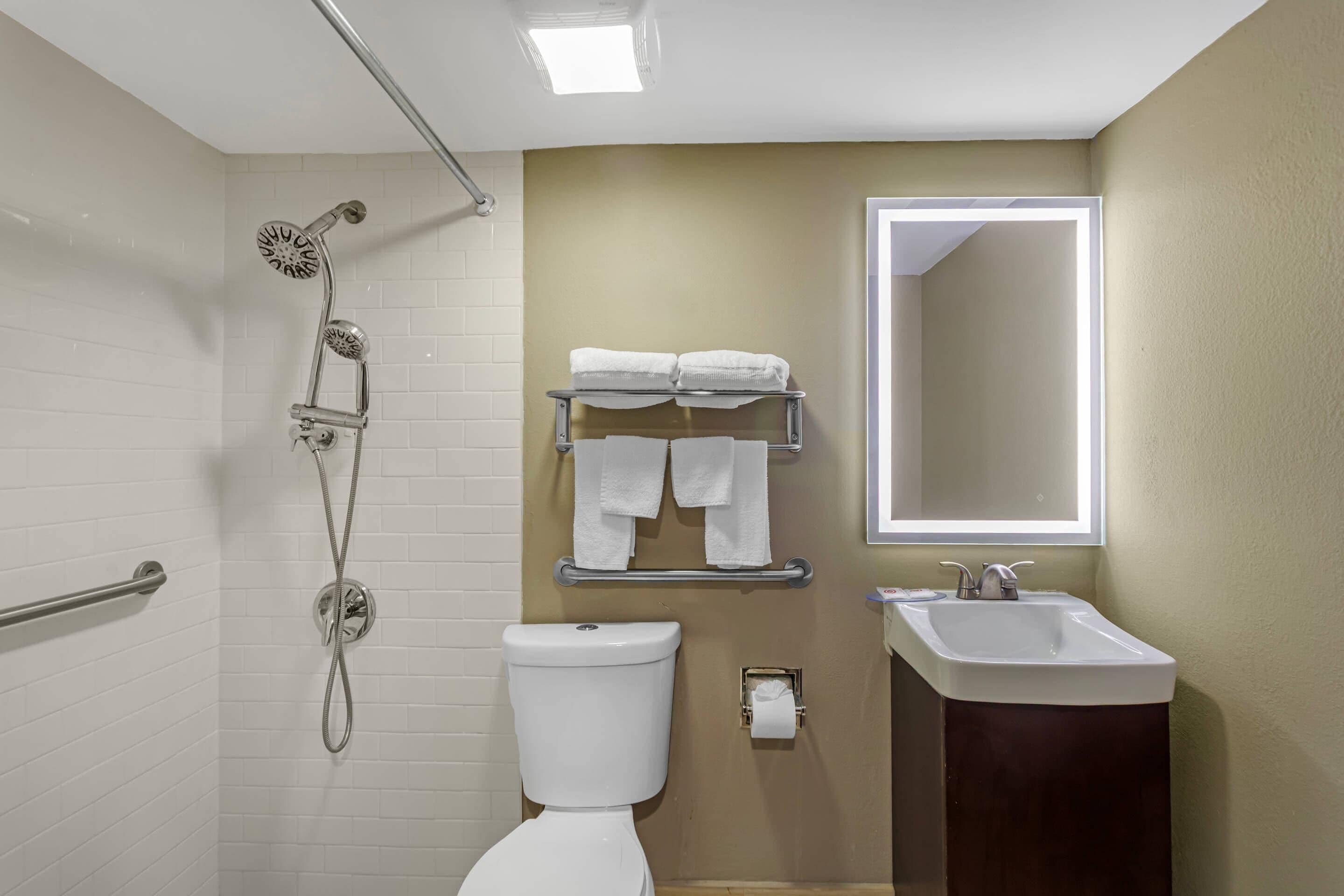 A bathroom with a shower, toilet, sink, and towel rack.