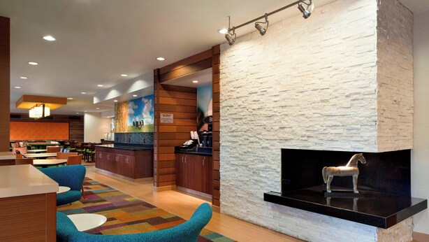 A modern lobby with a fireplace, seating area, and a kitchen in the background. - Fairfield Inn & Suites by Marriott Branson (Branson)