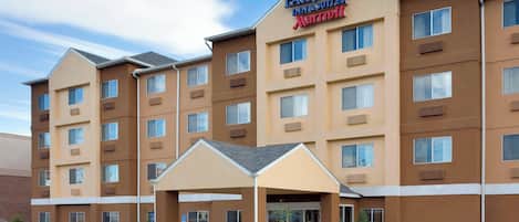 Un hôtel Fairfield Inn & Suites de la chaîne Marriott, doté d’une entrée centrale, d’un espace extérieur couvert et d’un parking avec des places délimitées.