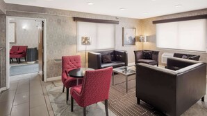 A modern hotel lobby with a seating area, a reception desk, and a large window.