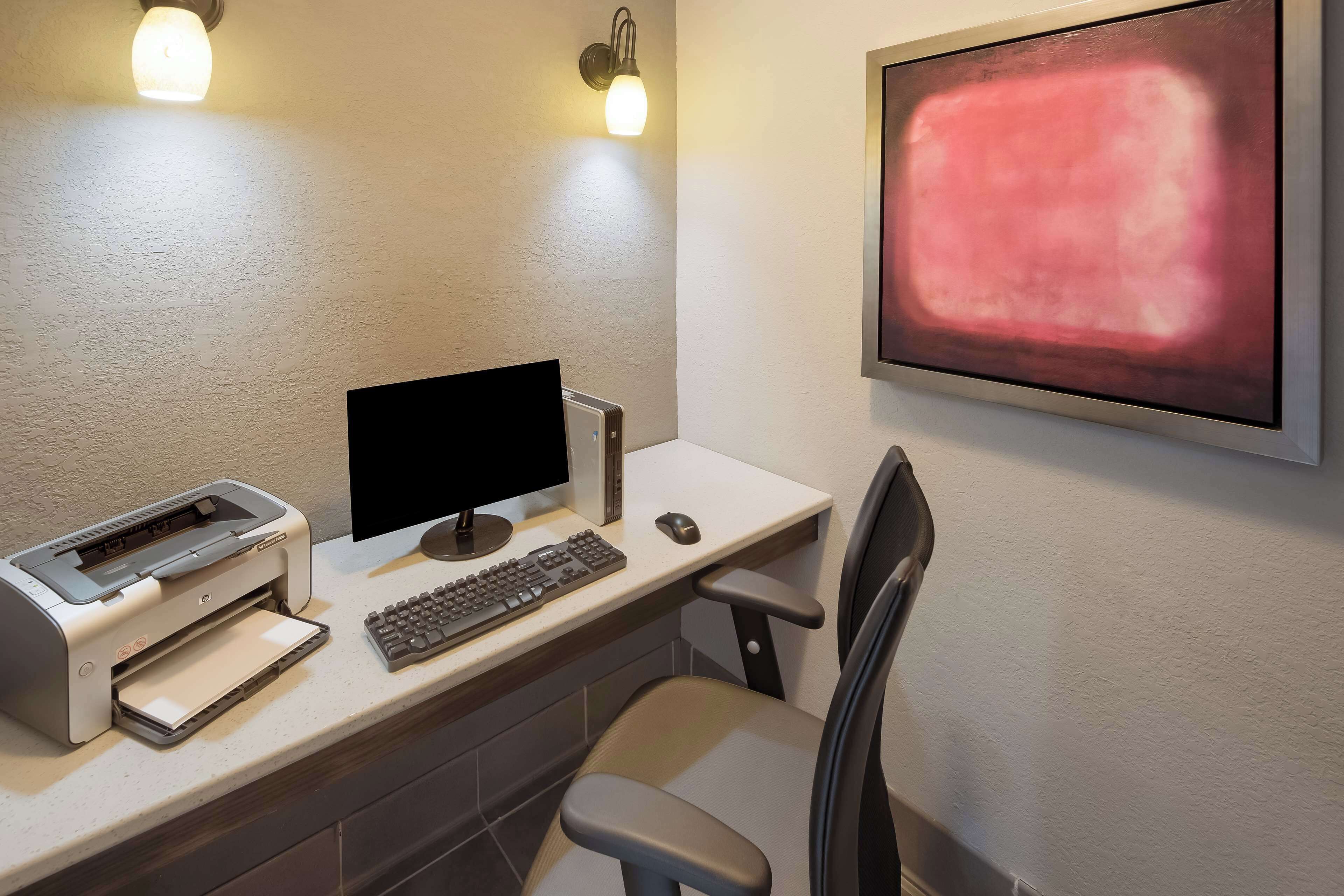 Un espacio de trabajo con un ordenador de escritorio, una impresora y una silla.