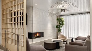 Una sala de estar moderna con chimenea, asientos cómodos y una planta decorativa.