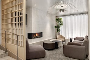 A modern living room with a fireplace, comfortable seating, and a decorative plant.