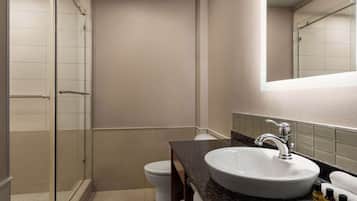 A modern bathroom with a glass-enclosed shower, a white sink, and a toilet.