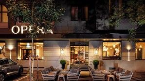 An outdoor seating area with tables and chairs in front of a hotel entrance.