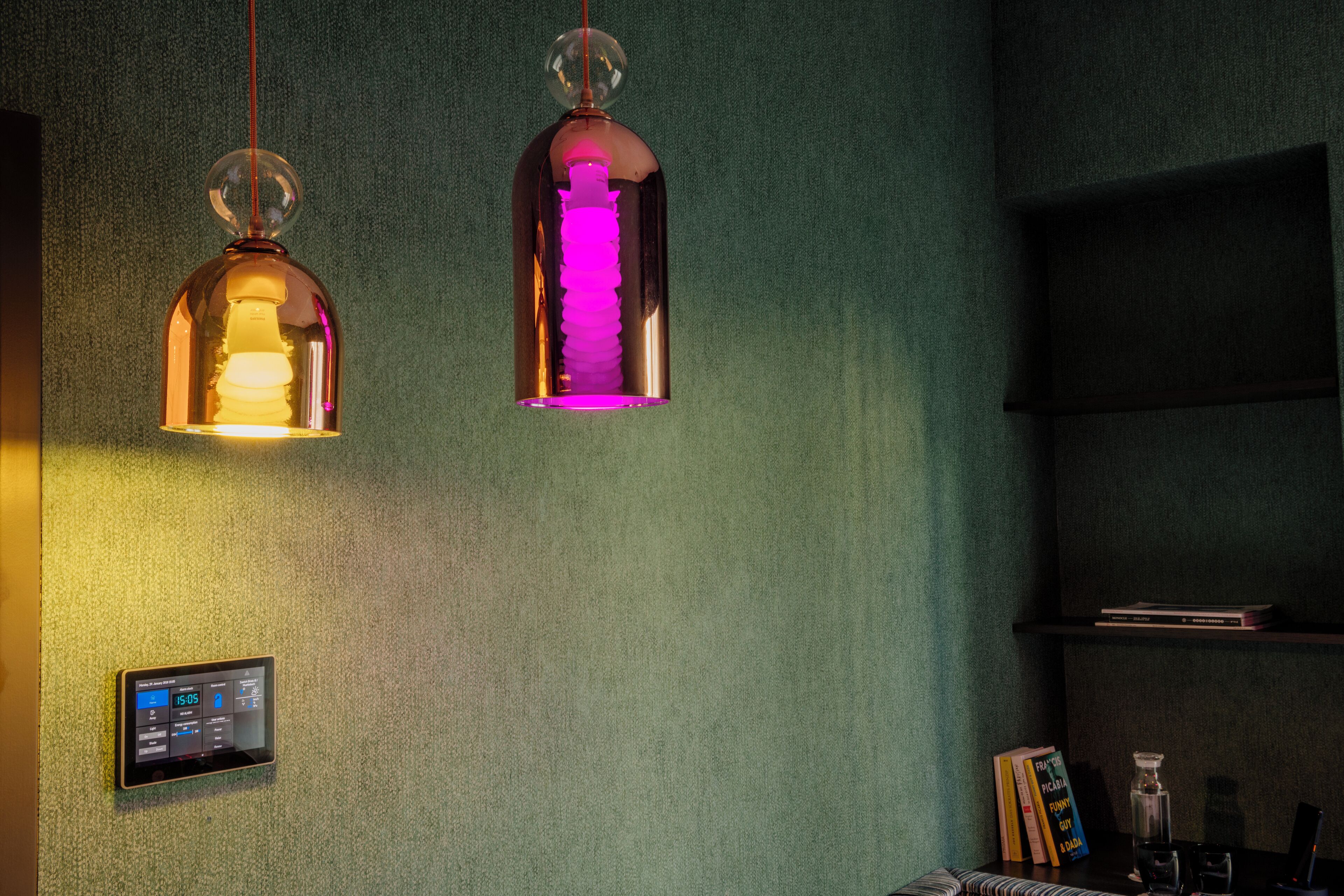 Dos lámparas colgantes con parte superior esférica y base cilíndrica, suspendidas del techo en una habitación con pared verde texturizada.