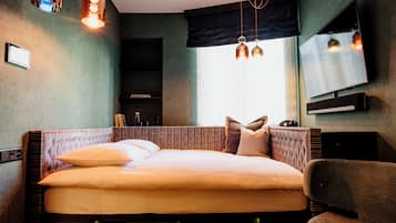 A modern hotel room with a large bed, a flat-screen TV, and ambient lighting.