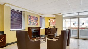 A lobby with brown leather chairs, a glass coffee table, and a fireplace. - Days Inn by Wyndham Silver Spring (Silver Spring)