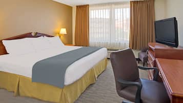 A hotel room with a bed, a desk with a television, and a chair.
