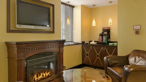 A hotel room with a fireplace, a TV mounted on the wall, a coffee machine, and a leather chair. - Days Inn by Wyndham Silver Spring (Silver Spring)