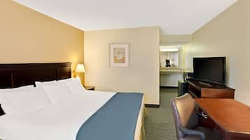 A hotel room with a bed, a desk, a chair, a television, and a framed picture on the wall.