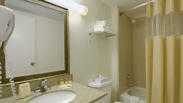 A bathroom with a sink, mirror, toilet, and shower.