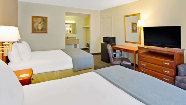 A hotel room with two beds, a desk with a computer, a television, and a dresser. - Days Inn by Wyndham Silver Spring (Silver Spring)