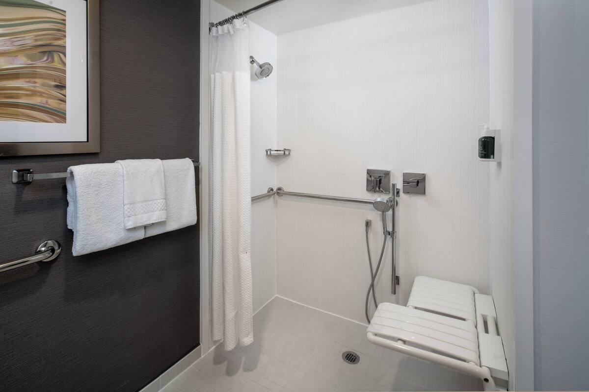 Ein modernes Badezimmer mit Dusche, Handtuchhalter und Haltegriff.