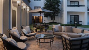 A courtyard with outdoor seating, including chairs and a table, and a glass-top coffee table.