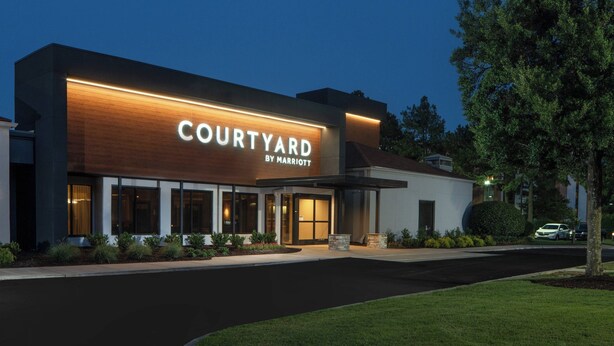 A Courtyard by Marriott hotel at dusk with a modern facade, large windows, and a well-lit entrance.