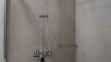 A shower with a handheld showerhead and a wall-mounted faucet.
