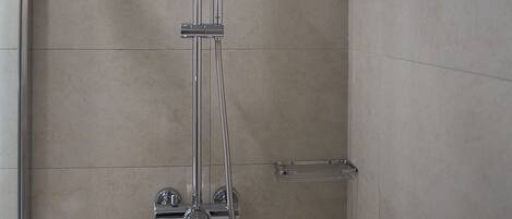 A shower with a handheld showerhead and a wall-mounted faucet.