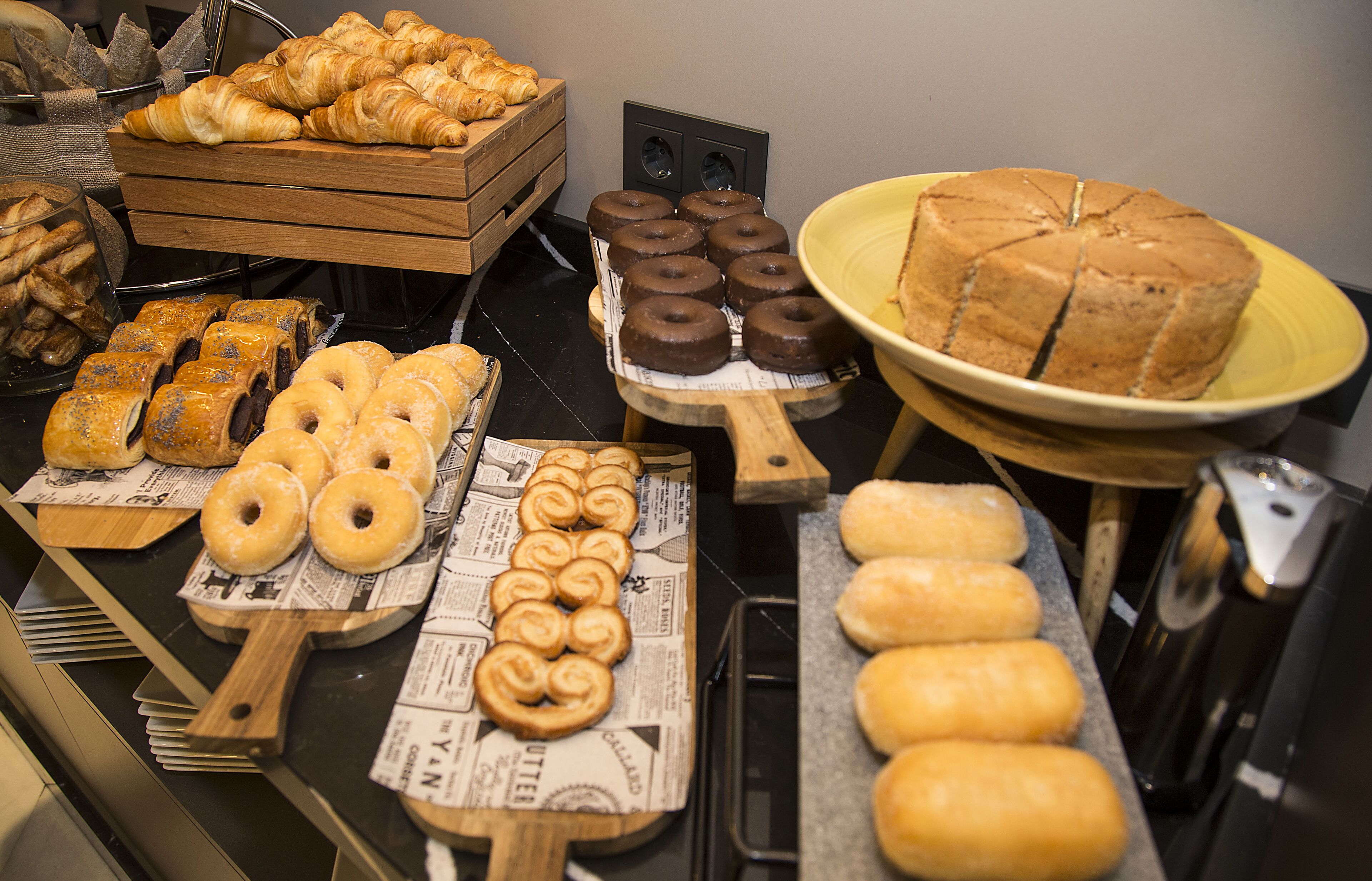 Een bakkerijdisplay met diverse gebakken producten, waaronder croissants, donuts en taarten.