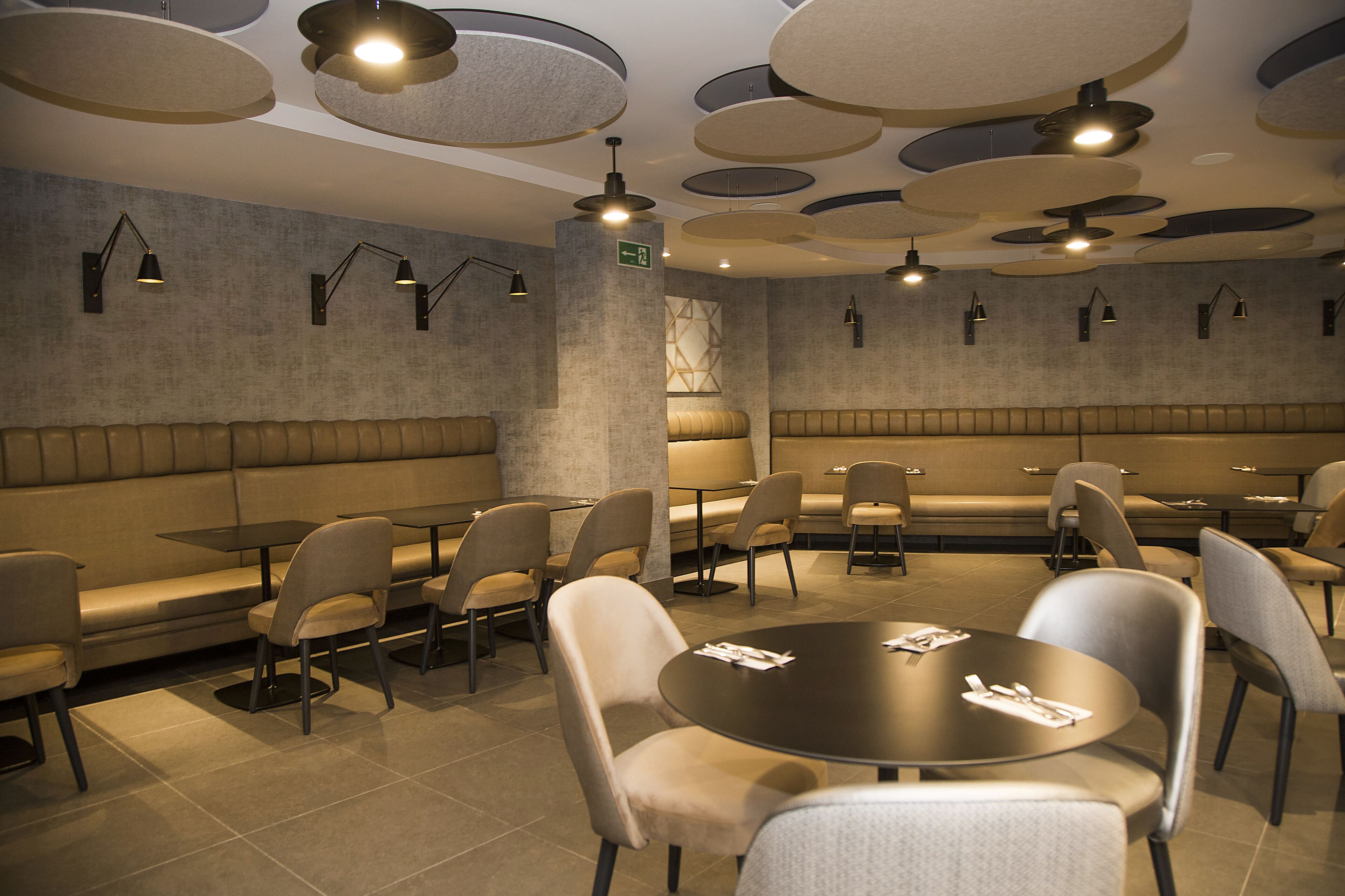 Un restaurante moderno con mesas redondas y asientos acolchados.