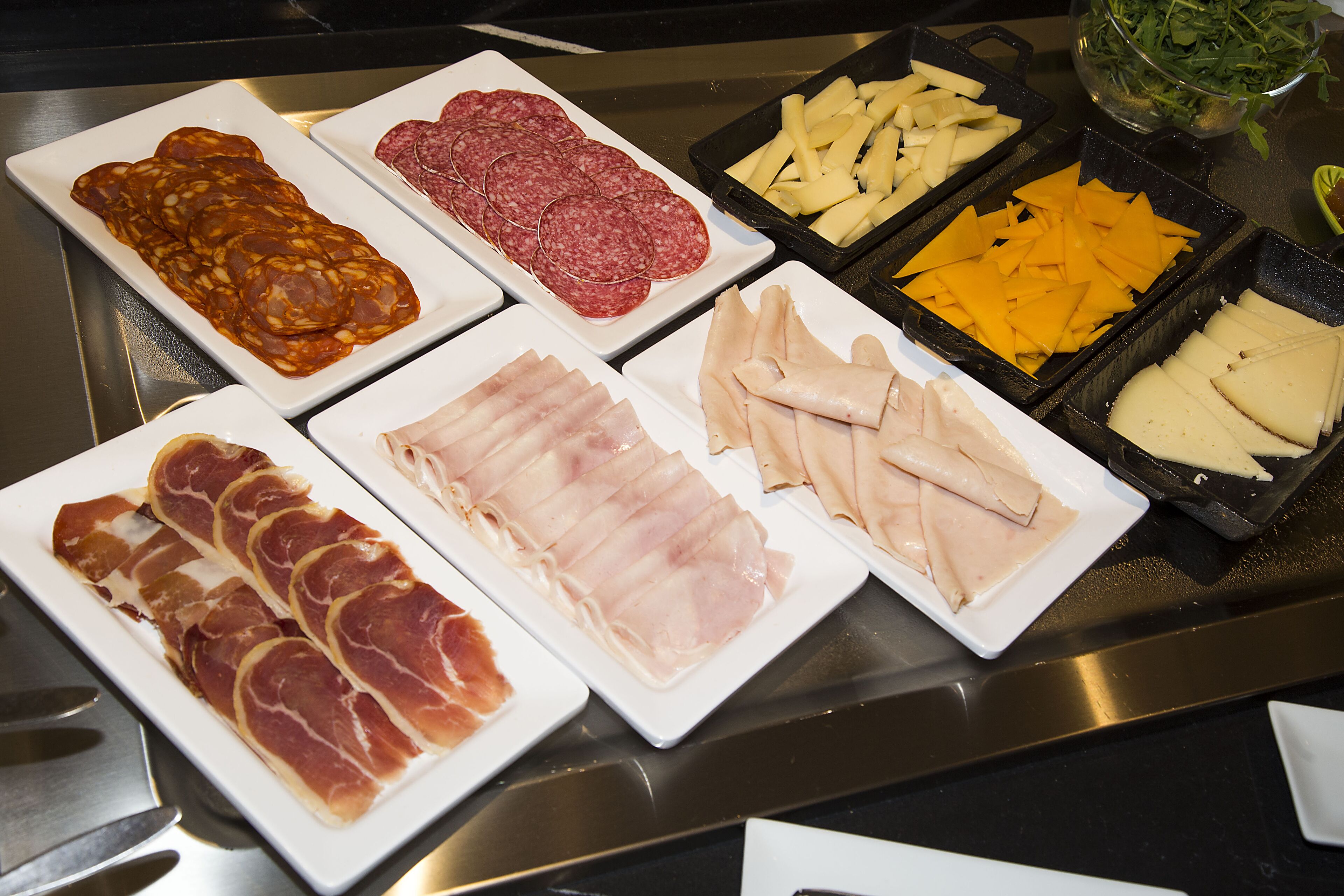A buffet with various types of meats and cheeses.
