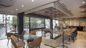Un café moderno con divisiones de vidrio, mesas y sillas.