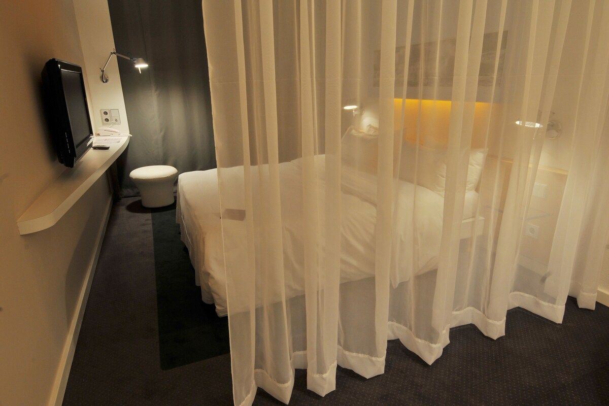 Une chambre d’hôtel équipée d’un lit, d’une télévision, d’un bureau et de toilettes.