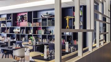 A modern library with bookshelves, a dining area, and a decorative sculpture.