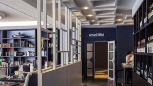 Een hotel lobby met een receptiebalie, een boekenkast met boeken en decoratieve objecten, en een wijnrekken.
