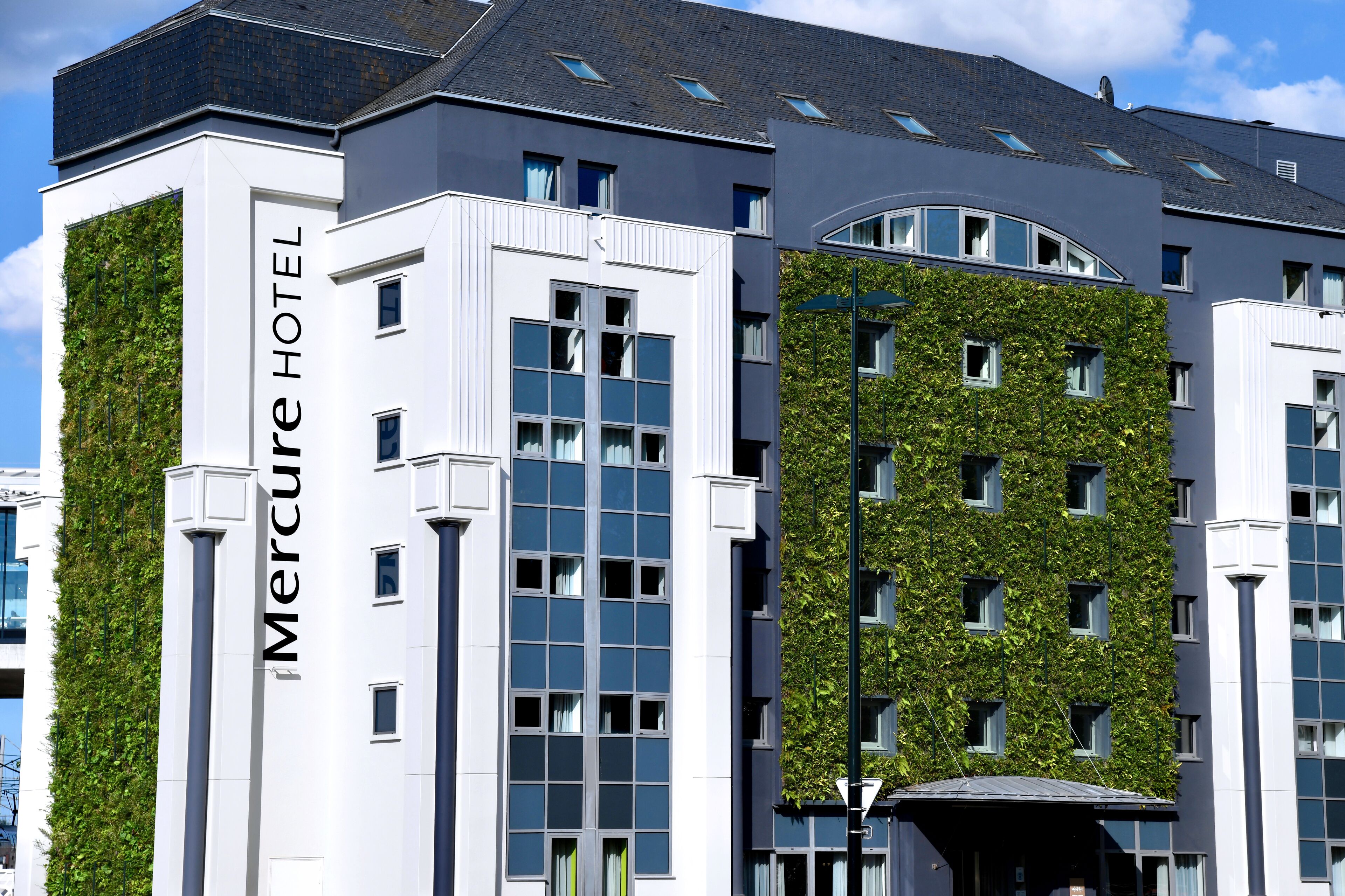 Un hotel moderno con fachada de jardín vertical, amplias ventanas y señalización destacada del 'Mercure Hotel'.
