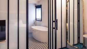 Een moderne badkamer met een zwart-wit geruite vloer, een badkuip, een wastafel en een spiegel met gouden lijst.