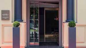 The entrance to the Mercure Hotel with a glass door, a sign above the door, and two potted plants on either side. - Mercure Nantes Centre Gare (Nantes)