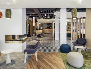 Een moderne lobby met een receptiebalie, een zithoek en een bar.